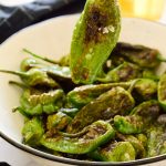 Fried padron peppers in a white bowl.