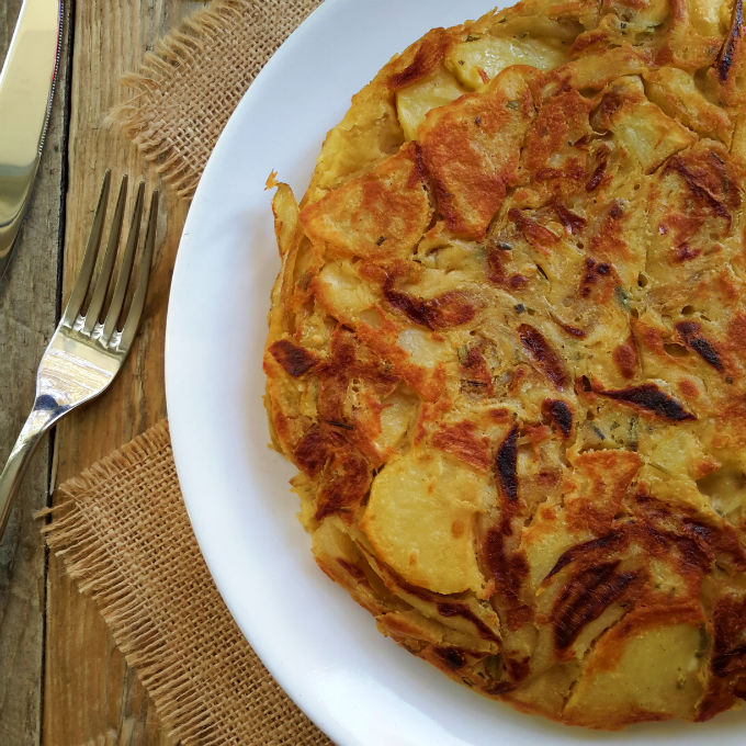 Vegan Spanish omelet with caramelized onions, roasted garlic and rosemary. An easy and delicious take on the traditional tortilla de patatas.