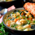 White bean and kale soup in a black bowl