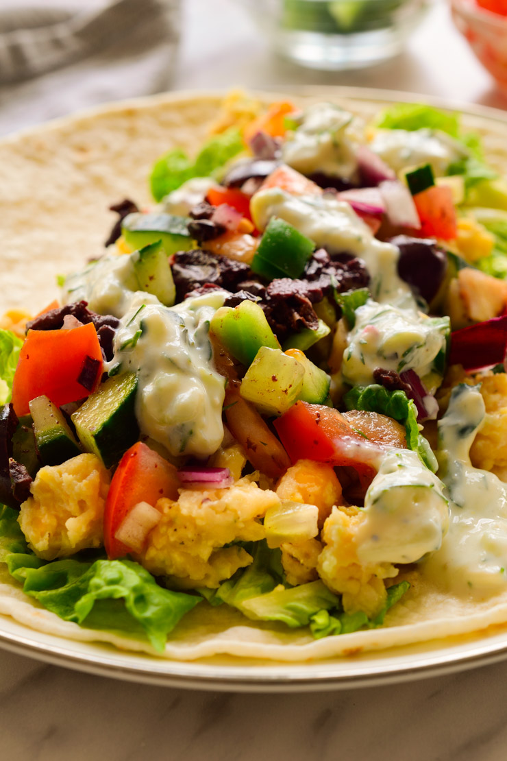 Un burrito vegano abierto y lleno de verduras, garbanzos y lechuga.