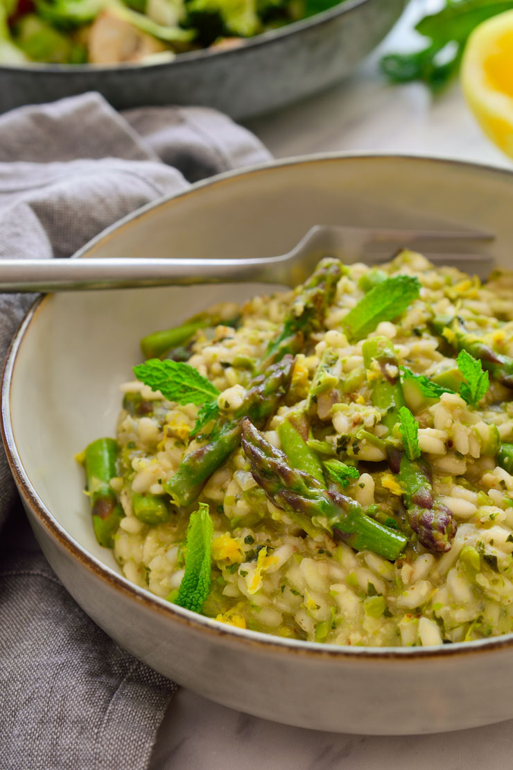 Vegan risotto with asparagus and mint-pea pesto served in a bowl.