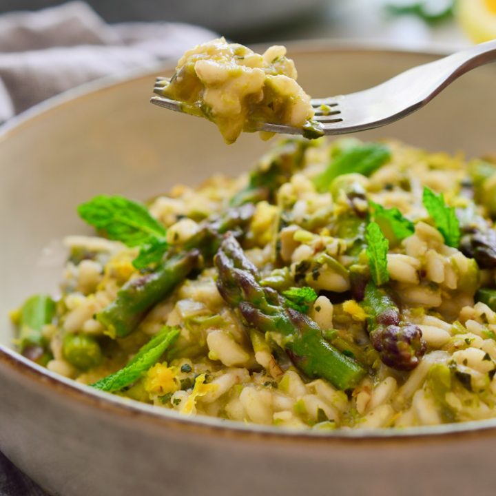 Vegan risotto with asparagus and mint-pea pesto served on a fork.