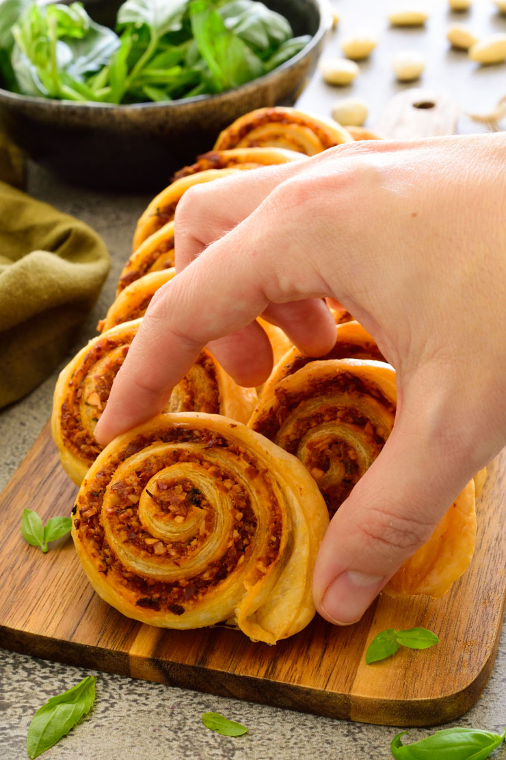 A hand picking up vegan pinwheels from a platter.