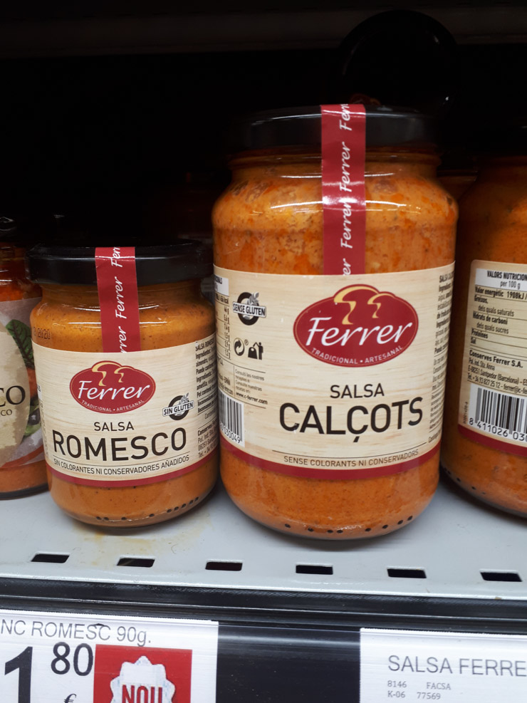 A jar of romesco and a jar of calçot sauce on the supermarket shelf.
