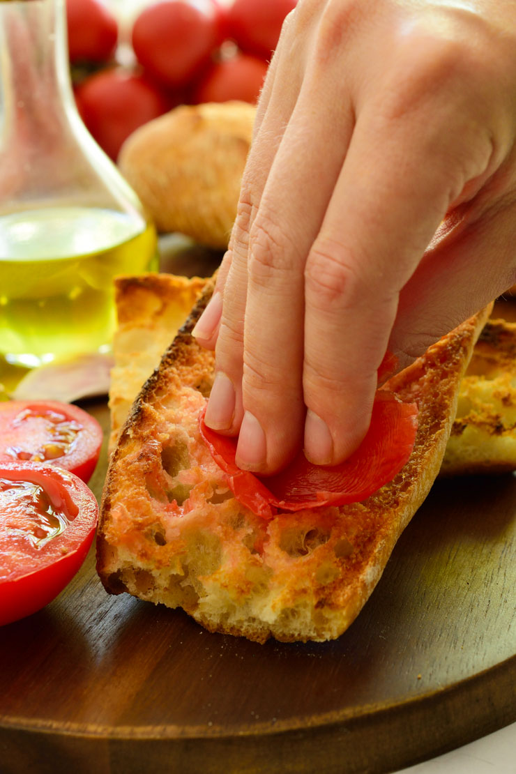 Rubbing a tomato on toasted bread.