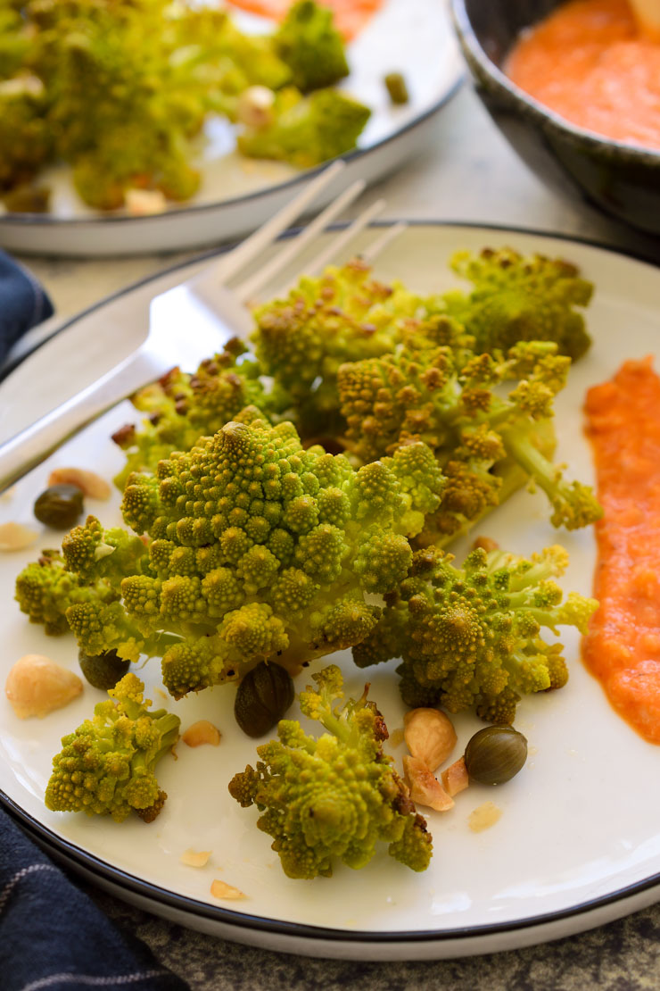 A top-down picture of roasted romanesco on a white plate.