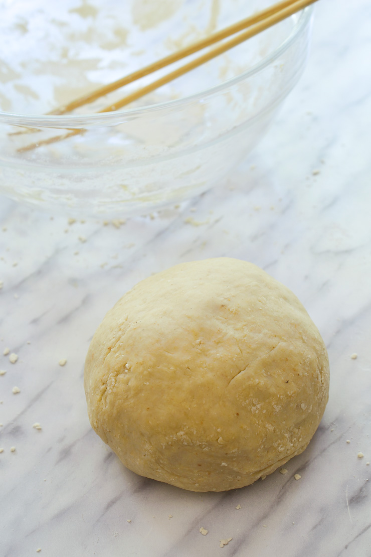 The smooth ball of dough on the counter ready to be rested. An empty bowl in the back.